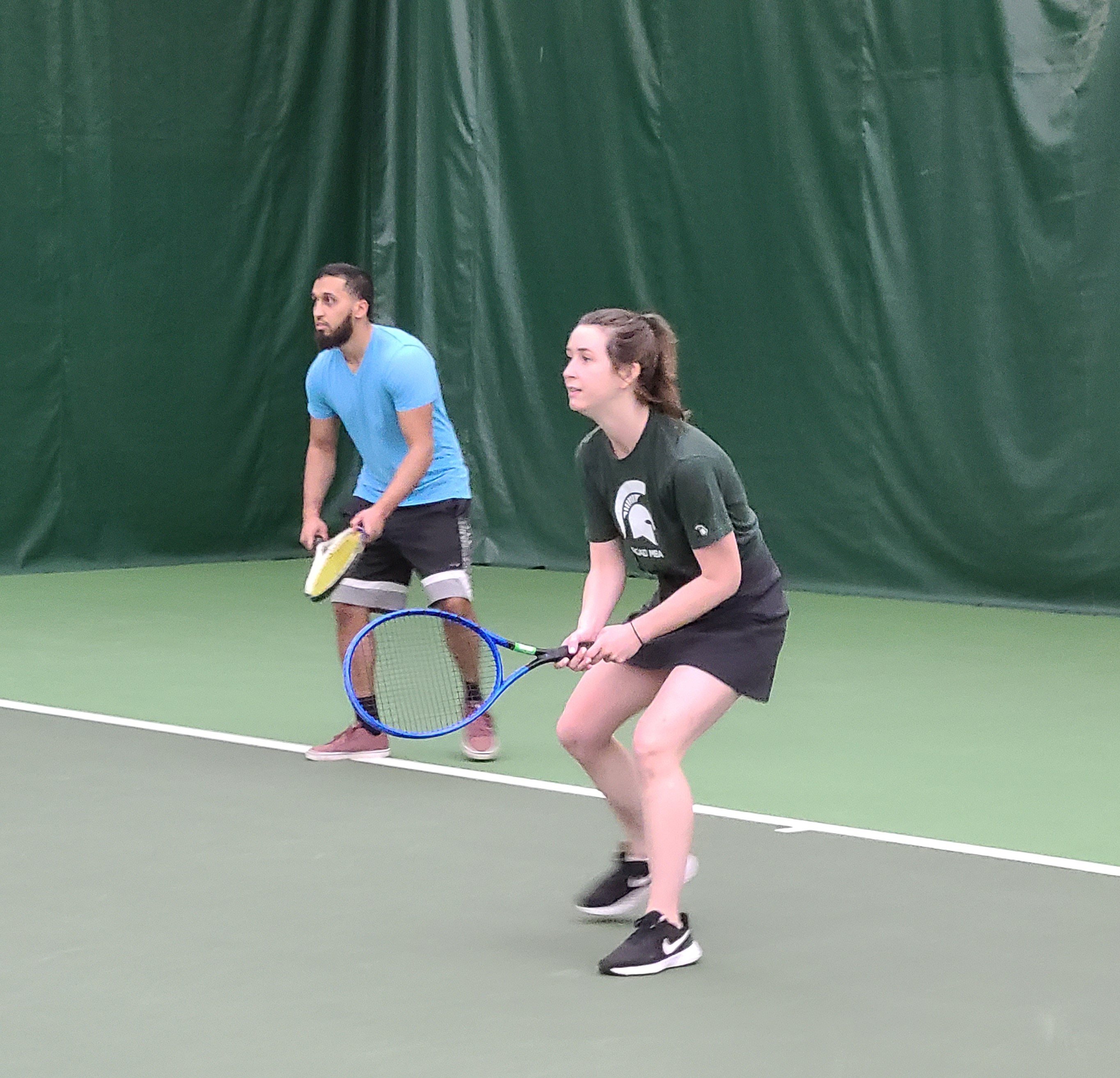two people waiting to return serve on tennis court
